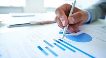Finanzierung Unternehmen Investitionen Hand mit Stift zeigt auf Diagramme